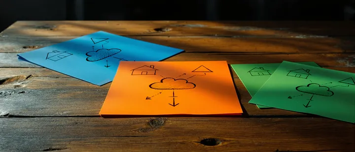 Three squared sheets of paper lie on a table. They have different colors but show all the same image:
A cloud symbol connected to a home symbol and a triangle symbol.
