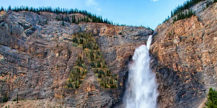 A scenic view of mountain cliff, a waterfall running down the cliff, an AWS Lambda logo shaped group of trees on the cliff.